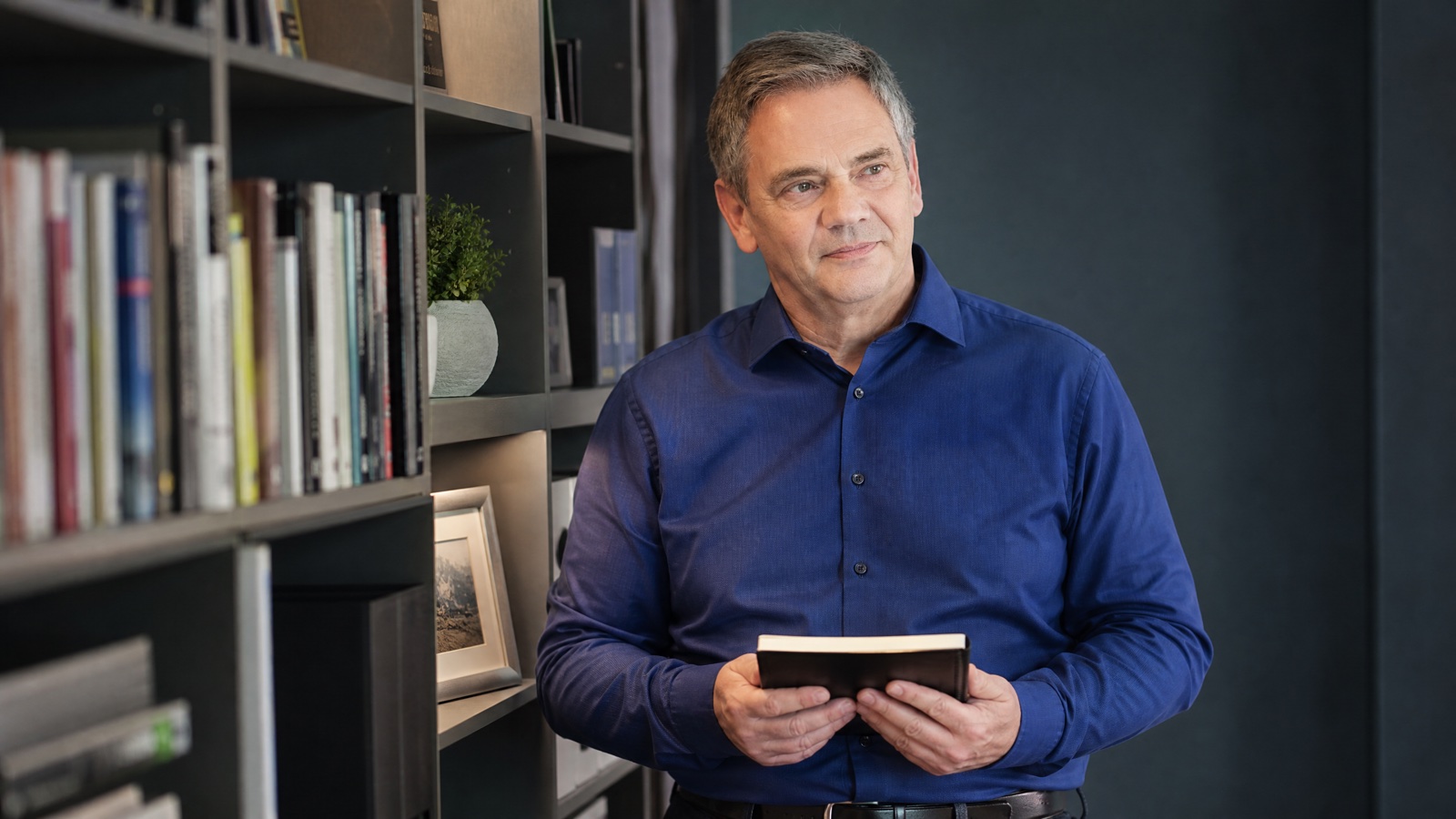 Ulrich Seyfferth nachdenklich am Bücherregal